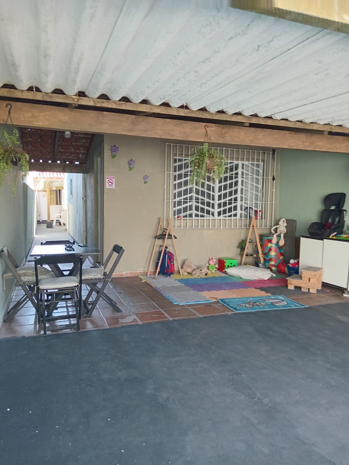 Área gourmet coberta da Kadiniz House com mesa, tapetes coloridos e cantinho das crianças